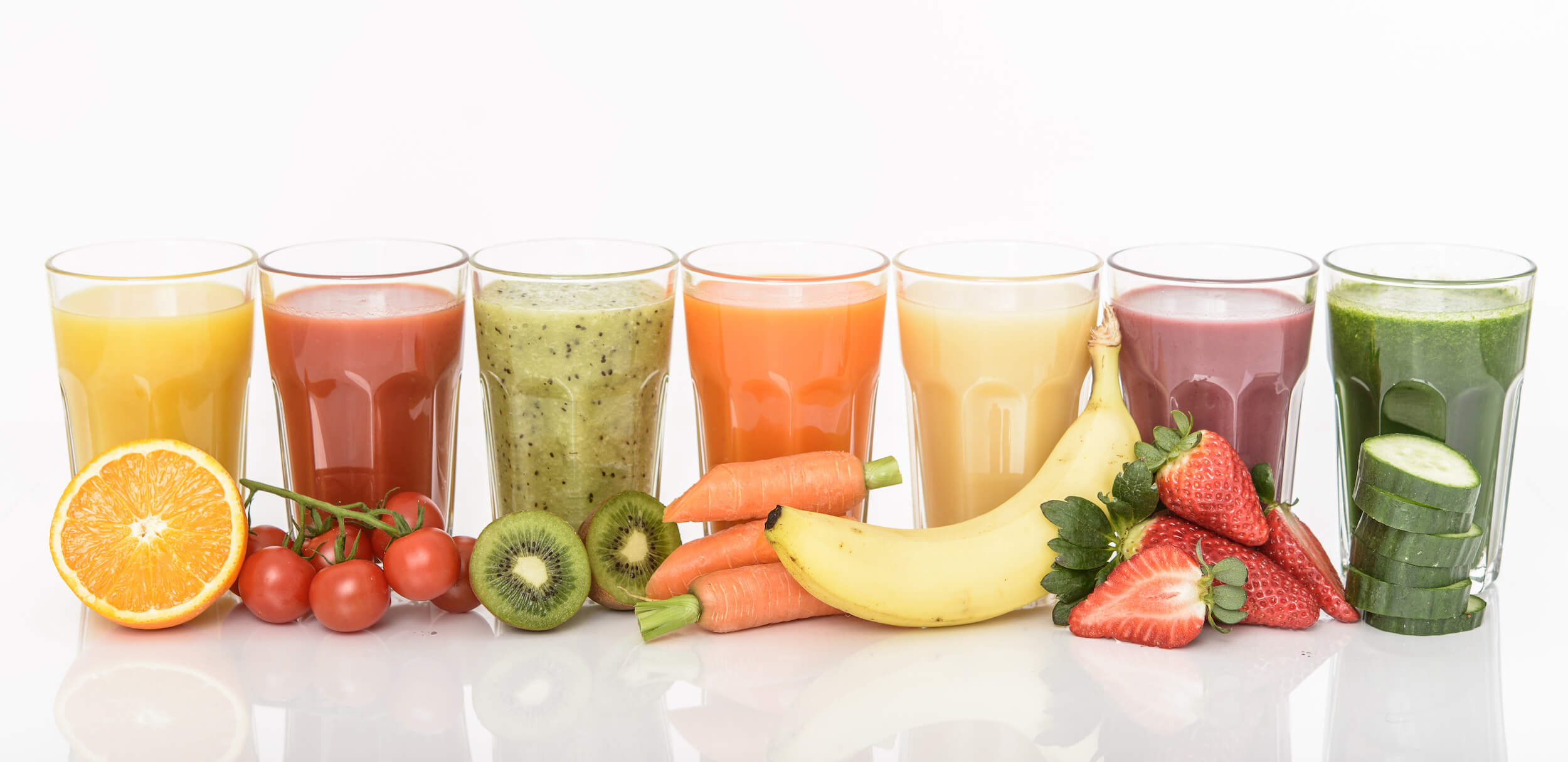 Aligned glasses filled with various types of juices, with the main ingredient in front of each glass